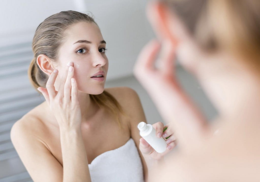 Young woman applying cream